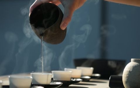 A hand pouring tea into small tea cups