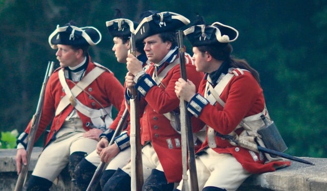 Soliders in Revolutionary war outfits with guns
